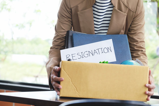 Businesswoman resignation packing up all her personal belongings and files into a brown cardboard box.