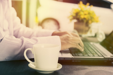 Cup of coffee and Businessman typing on keypad  in shop