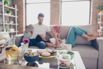 Sweet life and sweet couple in love. Food is in a focus on the background of happy beautiful couple, which is spending weekend together on couch indoors at home