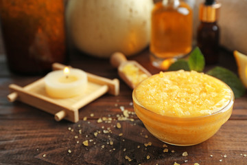 Glass bowl with lemon scrub and sea salt on wooden table