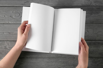 Female hands leafing through opened book with blank pages on wooden background