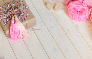 Pink tassels. Background of white wood. Women's handicrafts. The concept of creativity.