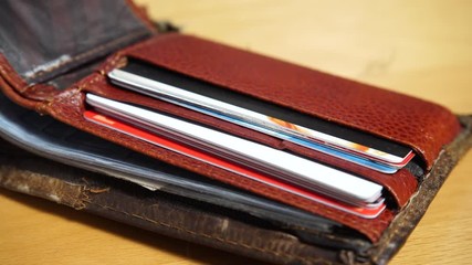 Nobody. Open leather brown male wallet with credit and discount cards on wooden table. Business and finance purse. Dolly sliding shot 4K ProRes HQ codec