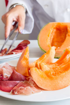 chef preparing dish with melon and ham