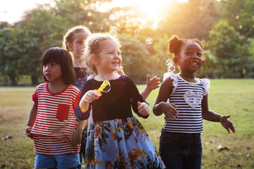 Group of kindergarten kids friends playing blowing bubbles fun