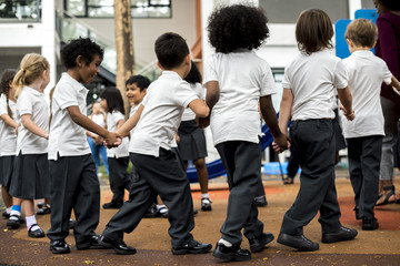 Group of diverse kindergarten students standing holding hands together