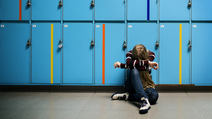 Boy sitting alone resting head on his arms