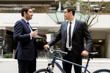 Two young businessmen with a bike in city centre