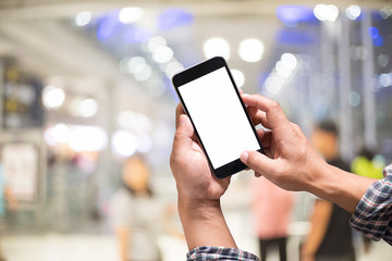 Man holding smart phone with blurred airport terminal background. Blank screen for Graphic display montage..