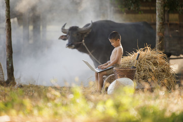 Asian country boy playing computer notebook on farm background
