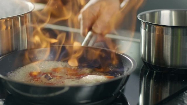Close-up of a Chef Preparing Flambe Style Dish on a Pan. Oil and Alcohol Ignite with Open Flames. Shot on RED EPIC-W 8K Helium Cinema Camera.