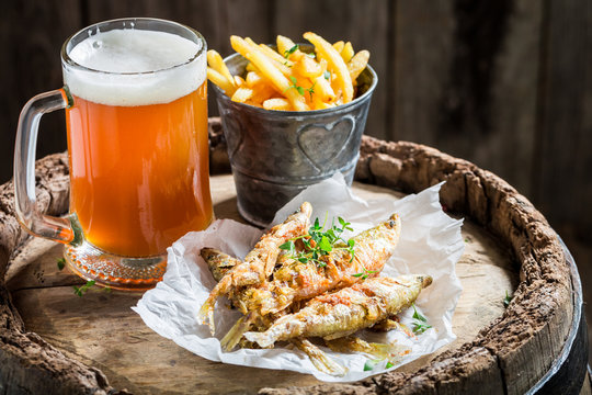 Smelt fish and chips with cold beer on old barrel