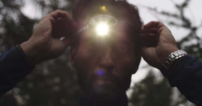 man wearing headlamp with approaching dark night. Group of friends summer adventure journey in mountain nature outdoors. Travel exploring Alps, Dolomites, Italy. 4k slow motion 60p video