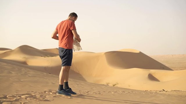 Young, lost man checking map on desert