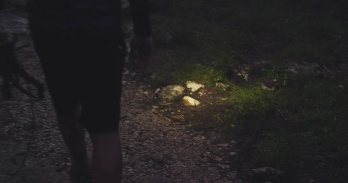 man walking in forest by night with headlamp light. Group of friends summer adventure journey in mountain nature outdoors. Travel exploring Alps, Dolomites, Italy. 4k slow motion 60p video