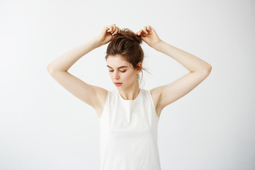 Young beautiful girl correcting hair bun over white background.