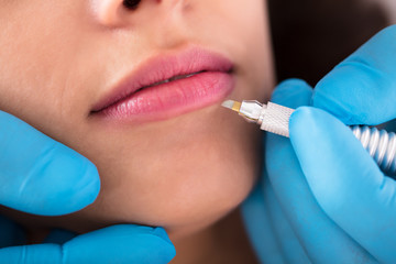 Cosmetologist Applying Permanent Make Up On Lips