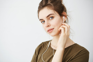 Portrait of young beautiful girl smiling listening music in headphones looking at camera over white background.