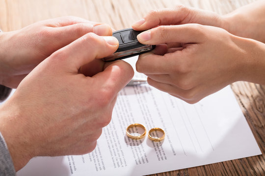 Couple's Holding Car Key Over The Divorce Agreement