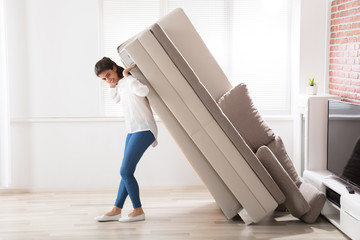 Woman Moving Sofa At Home