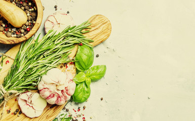 Food background, fresh rosemary, green basil, garlic, pepper on a cutting board, top view