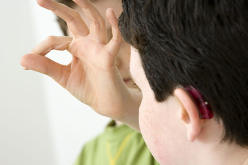 Fototapeta premium Models Do not use for HIV Young boy using the French sign language to discuss with his hearing-impaired brother The French sign language uses signs to designate words but also dactylology (each letter of the alphabet is represented by a defined position of the fingers then enabling to spell a word) and the lip reading The young boy designates the letter \t\ (see image nﾰ0833202 ans series of images from nﾰ0572308 to 0574108 to see the other letters of the alphabet)