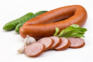A circle of sausages and slices of sausage, cucumbers, a head of garlic and a salad.