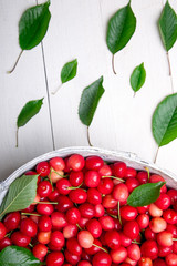 Red cherries in white basket on white wooden background. Cherry close up. Top view.