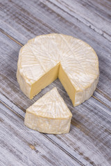 Brie type of cheese. Camembert cheese. Fresh Brie cheese and a slice on a wooden board. Italian, French cheese.