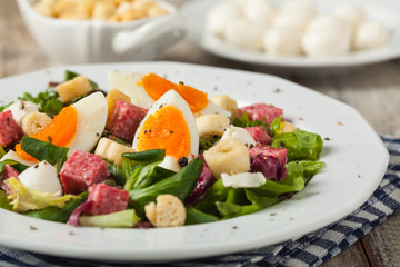 Delicious Italian salad with salami, egg, crostini and mozzarella.