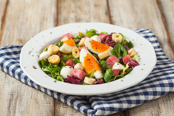 Delicious Italian salad with salami, egg, crostini and mozzarella.