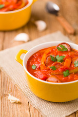 Delicious letcho with fresh vegetables, served in a yellow pot with the fresh bun.