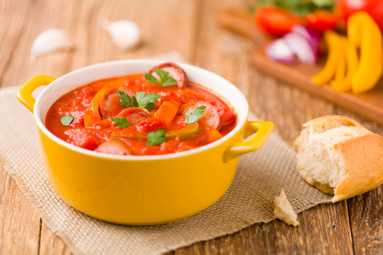 Delicious letcho with fresh vegetables, served in a yellow pot with the fresh bun.