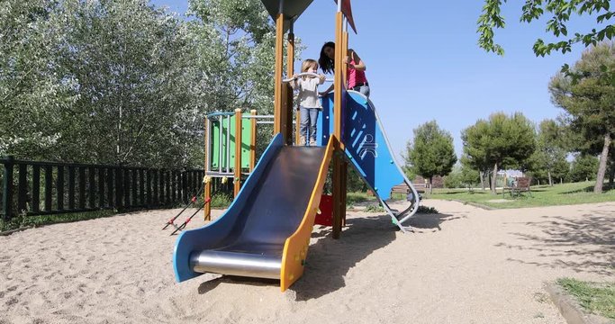 child and woman mother playing sliding in metal slide. Kid is three years old blonde. Outdoor playground, in public Park Valdebebas, Madrid Spain
