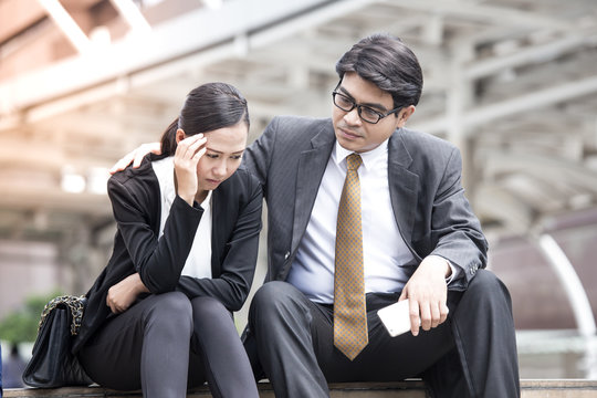 Asian businessman help woman in stress situation while sitting, business stressful concept.
