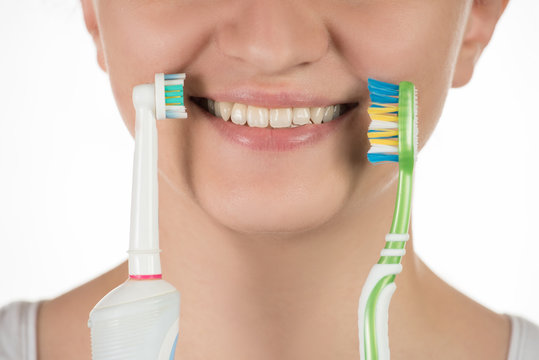 Hygiene of the oral cavity. A young girl chooses between an electric and a simple toothbrush.
