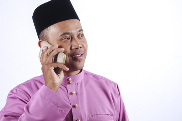 Man in traditional clothing with smartphone celebrate Eid Fitr.