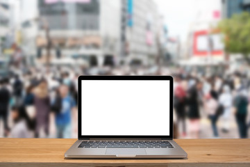 Laptop with blank screen on table with shibuya blurred background