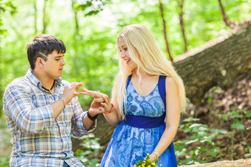 Fototapeta premium holidays, love, couple, relationship and dating concept - romantic man proposing to a woman in the summer park