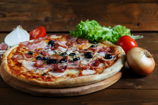 Delicious homemade pizza with mozzarella, ham, olives and fennel.