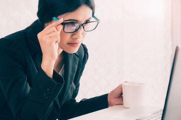 Asian Businesswoman working and holding coffee cup in office work space