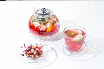 Red fruit and berry tea with raspberries in a glass teapot with mint isolated