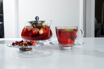 Red fruit and berry tea with raspberries in a glass teapot with mint isolated