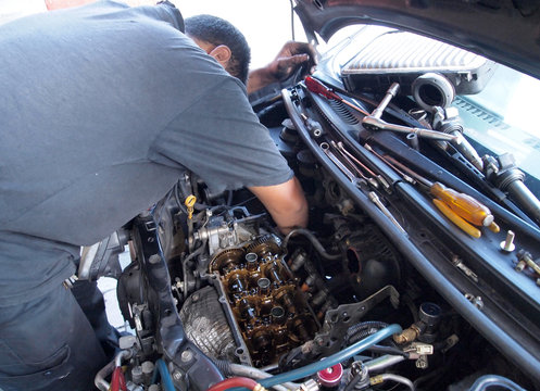 Car Mechanic Repairing Faulty Car Engine At The Workshop. 