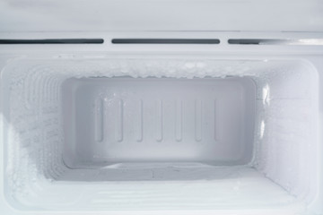 empty freezer of a refrigerator - Ice buildup on the inside of a freezer walls.  - obrazy, fototapety, plakaty