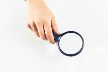 Hand with magnifying glass on white background