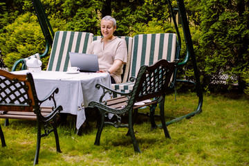 Middle age short gray hair woman with tablet sitting at indoor cafe looking for screen