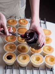Baking cupcakes. Filling jam by spoon