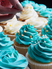 Making cupcakes with cream. Sprinkling stars