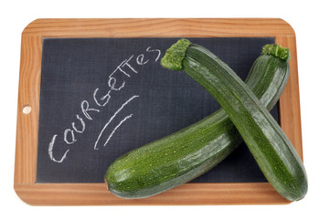 Courgettes écrit sur une ardoise sur laquelle sont posées des courgettes